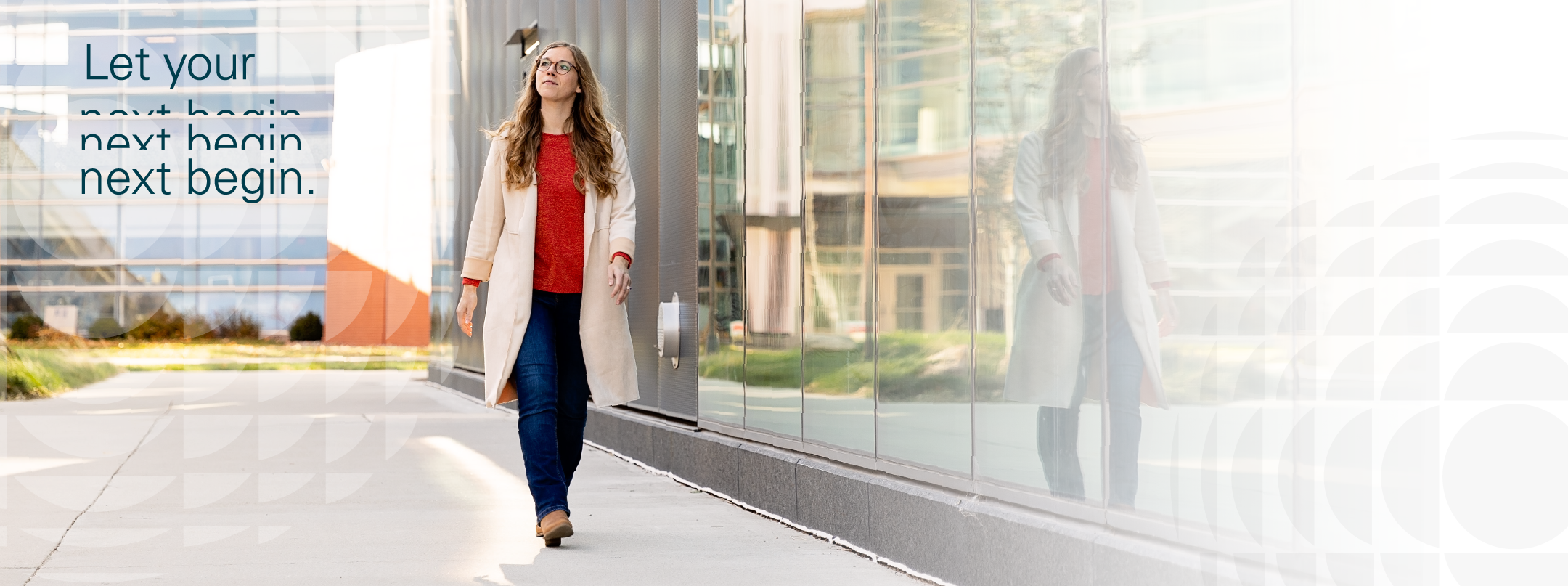 Woman walking on a sidewalk next to a glass paned building